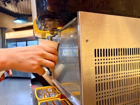 Hand Pouring Beverage from Dispenser into Paper Cup
