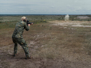Fototapeta premium A Dutch soldier in NFP fractal camouflage fires a British bullpup assault rifle from the standing position during allied live fire training.