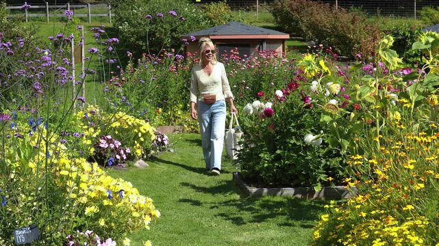 Woman walking in a beautiful blooming flower garden.