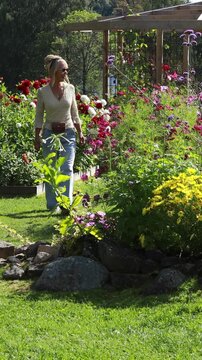 Woman walking in a beautiful blooming flower garden. Vertical design in 9:16 ratio. Smartphone and social media ready.	