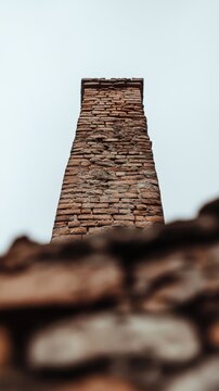 Weathered damaged brick chimney ruins closeup low angle view against cloudy sky
