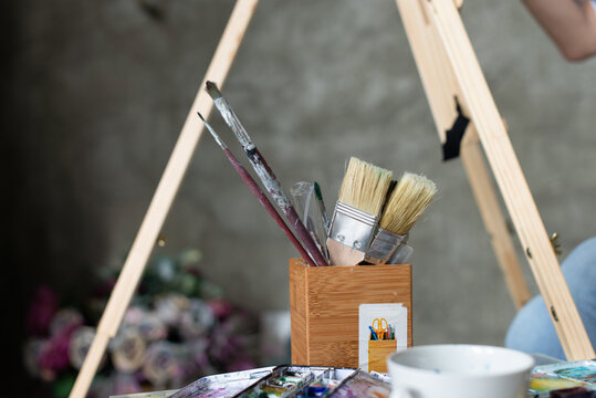 Watercolour artist tools beside easel in creative studio