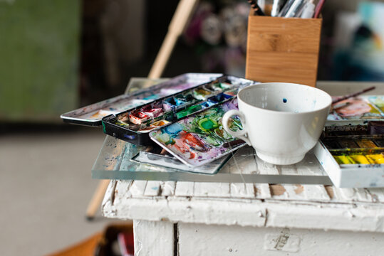 Watercolor artist workspace with palette and ceramic cup