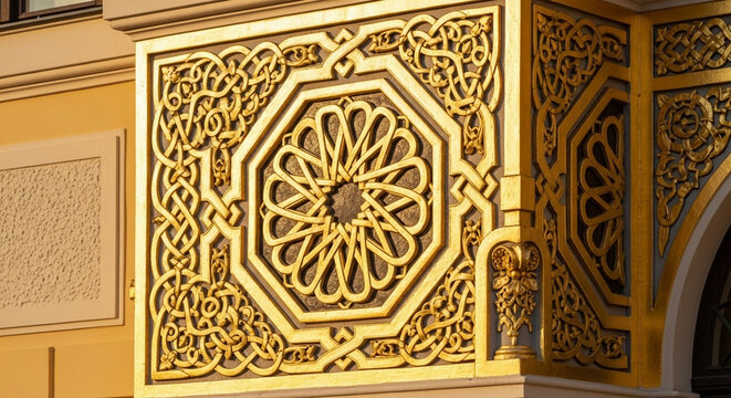 A stunning golden architectural carving features intricate geometric patterns and ornate relief motifs adorning the facade of an imposing historic building during bright daylight hours