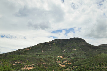 Fototapeta premium Green Mountain Slopes Under Clouds and Blue Sky