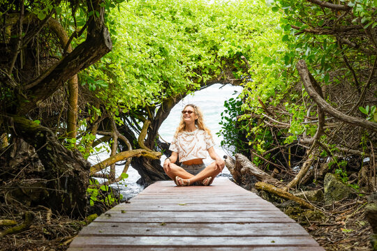Woman meditate on Galapagos Island forest boardwalk