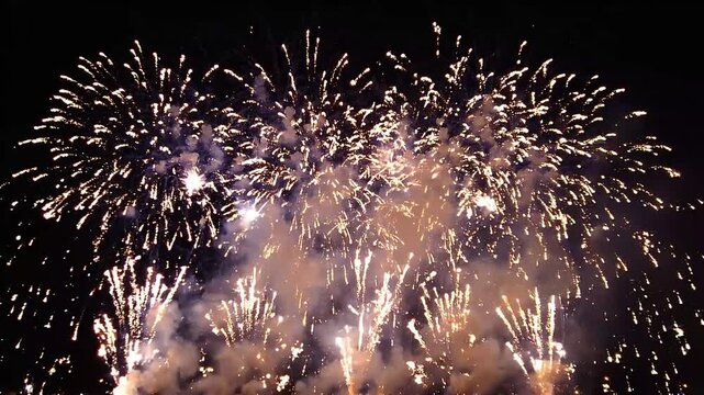 Spectacular night fireworks display explosion illuminating dark sky with bright bursts and smoke trails creating celebratory atmosphere for holidays and events.