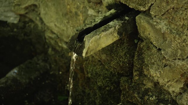 Fresh spring water flows from a stone spout in Kopaonik, Serbia. Natural mountain footage suits travel, hiking, wellness, ecology and hydration themes
