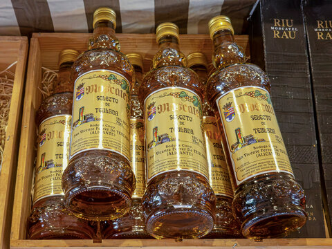 Jesus Pobre, Spain - August 16, 2026.Clear glass bottles of sweet wine arranged in a wooden crate in a market setting