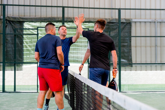 Padel doubles players celebrating with high five at net