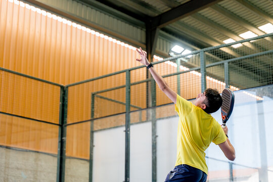 Padel player serve during indoor tournament match