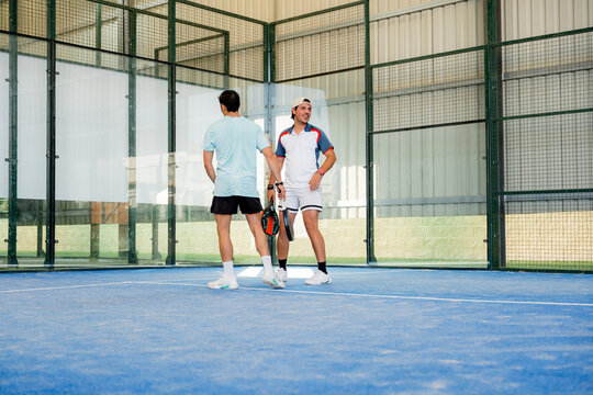Padel doubles partners converse on indoor tournament court