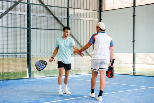 Padel tournament partners shake hands on indoor court