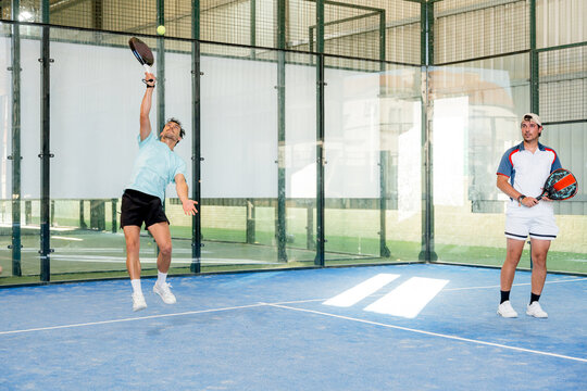 Padel player serve ball during indoor tournament match