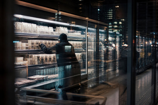Night Supermarket Restocking with Retail Worker and Refrigerated Aisle Reflections