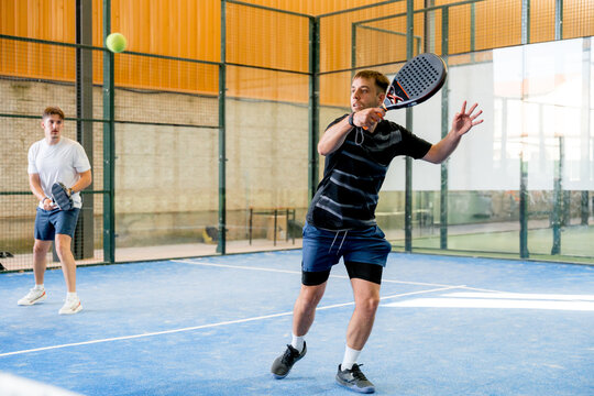 Padel player return ball during indoor tournament match
