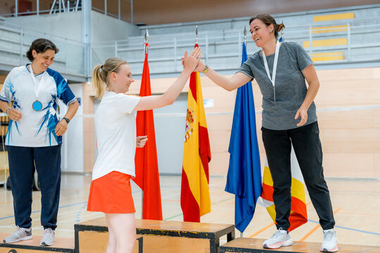 Female badminton players celebrate with high-five at tournament