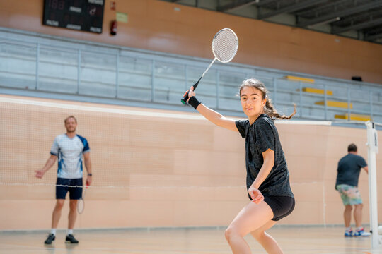 Female player practice badminton serve on indoor court