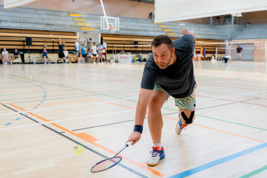 Male athlete return shuttlecock during indoor badminton tournament