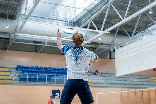 Badminton player serve during indoor tournament match