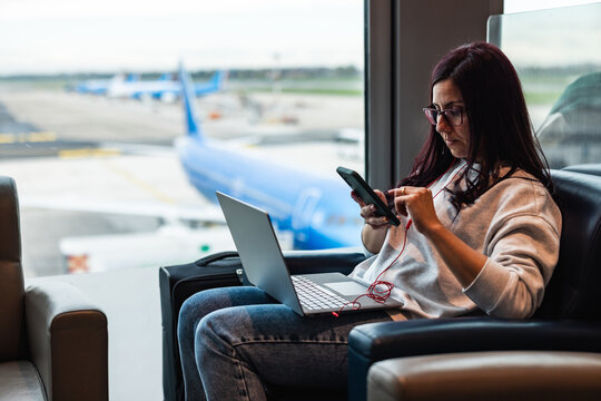 Woman using laptop and smartphone at airport lounge