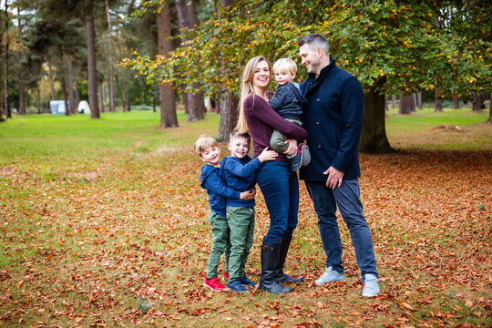 Family with three sons enjoying autumn day in park