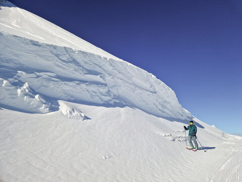 Skier on snowy mountain slope beneath clear blue sky