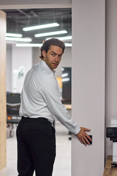 Young professional man swiping access card to enter modern office corridor during workday with focused expression and secure interior access, with man, professional, young, swiping detail