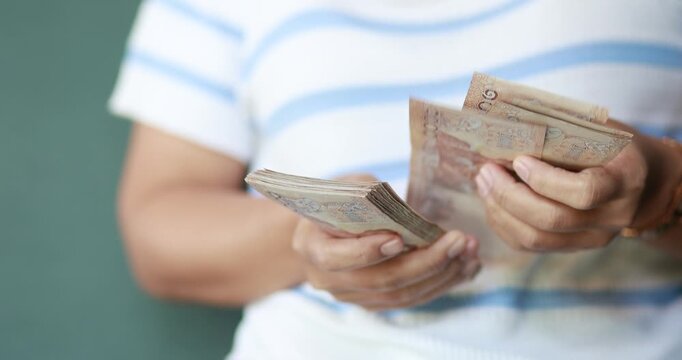 Hands counting Thai baht banknotes, finance and money, cash, savings, budgeting, income, expenses, investment, cash management, and financial security, close-up