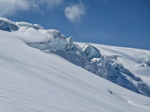 Snow-covered glacier crevasse beneath a clear blue sky