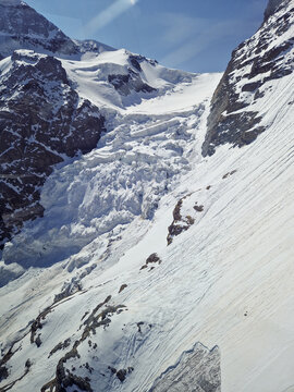 Snow avalanche on a steep alpine mountain slope