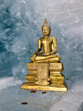 Golden Buddha statue in icy winter snow cave