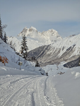 Snow-covered mountain road leading through a winter valley