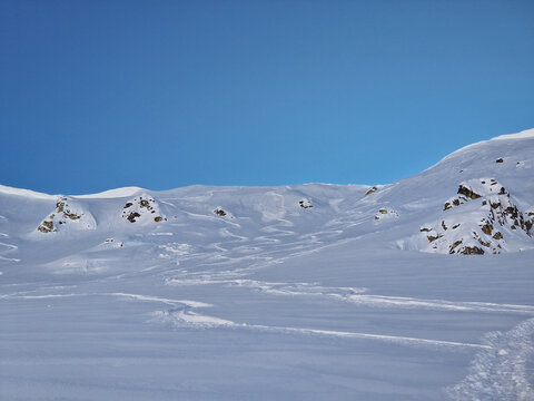 Snow-covered mountain slope beneath clear blue winter sky