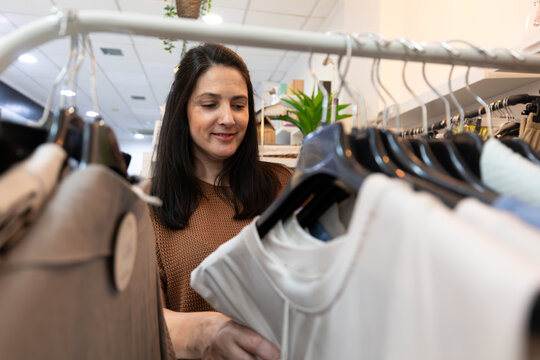 Female shop employee arranging clothes on retail rack