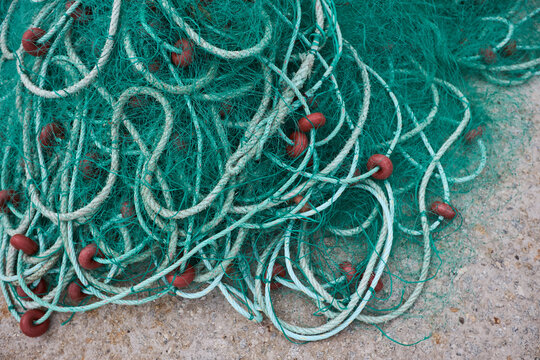 Tangled fishing net with rope and float on shore
