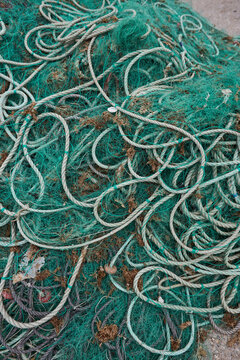 Tangled fishing net and rope on weathered coastal ground
