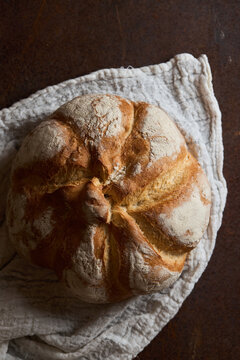 Rustic artisan bread loaf on linen cloth from above