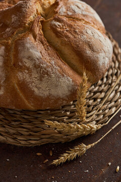 Rustic bakery bread loaf in woven basket with wheat