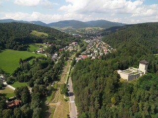 Muszyna - Polska Pięknie położone miasto w górach Beskidach zdjęcia wykonane dronem z powietrza. Zamek na wzgórzu, las, niebo, chmury, miasteczko, dolina, rzeka, lato, wiosna. © Konrad