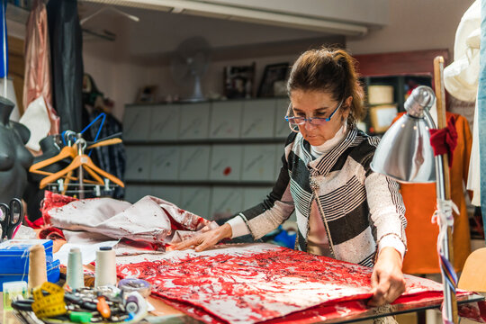 Dressmaker creating a handmade red lace gown in atelier