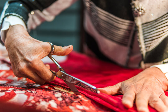 Tailor cut red fabric with scissors for handmade dress