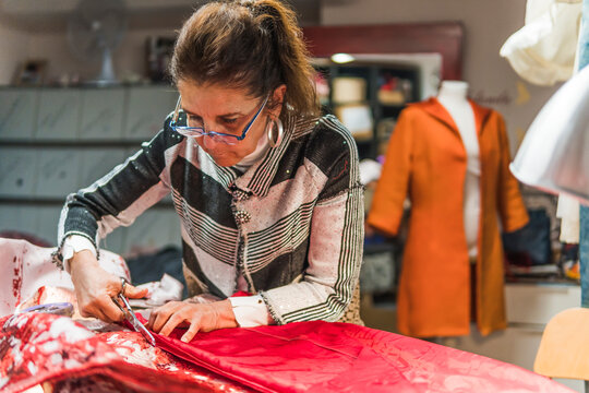 Fashion designer cut red fabric in clothing workshop