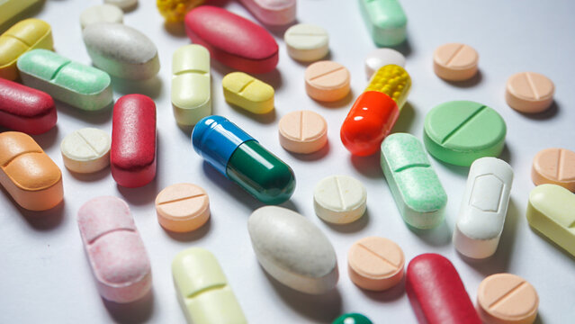 Colorful antibiotics and some health supplements are scattered on white surface. Medicines. 