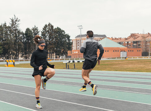 Athletes perform warm-up drills on an outdoor running track