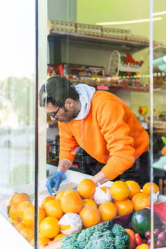 Shop worker arrange fresh citrus fruit at market display