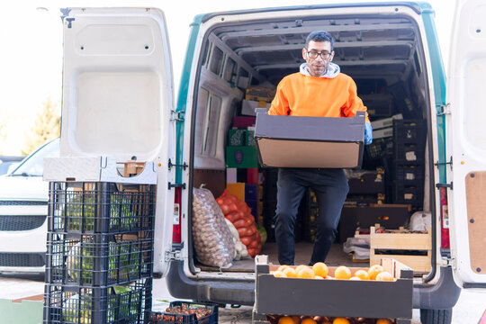 Market worker unloads fruit delivery from cargo van