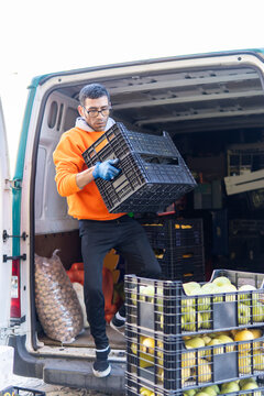 Fruit delivery worker unloads crate from cargo van