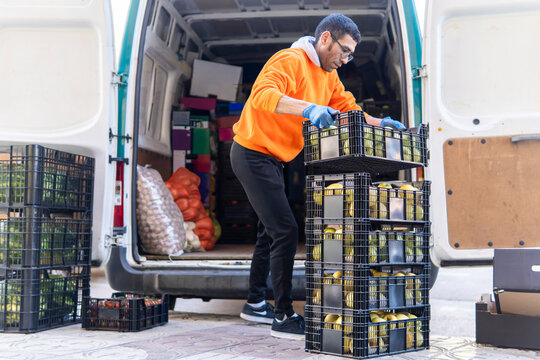 Delivery worker unloads fruit crates from cargo van