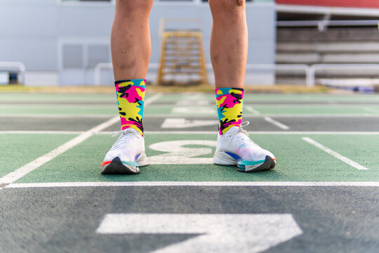Woman runner at track start line in colorful socks